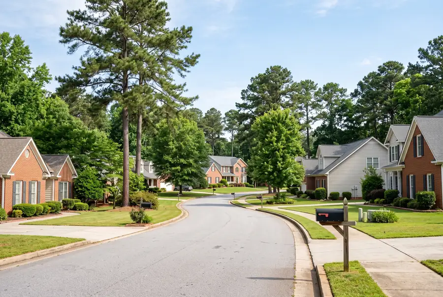 Quiet suburban neighborhood street with brick homes and pines in Paulding County, Georgia